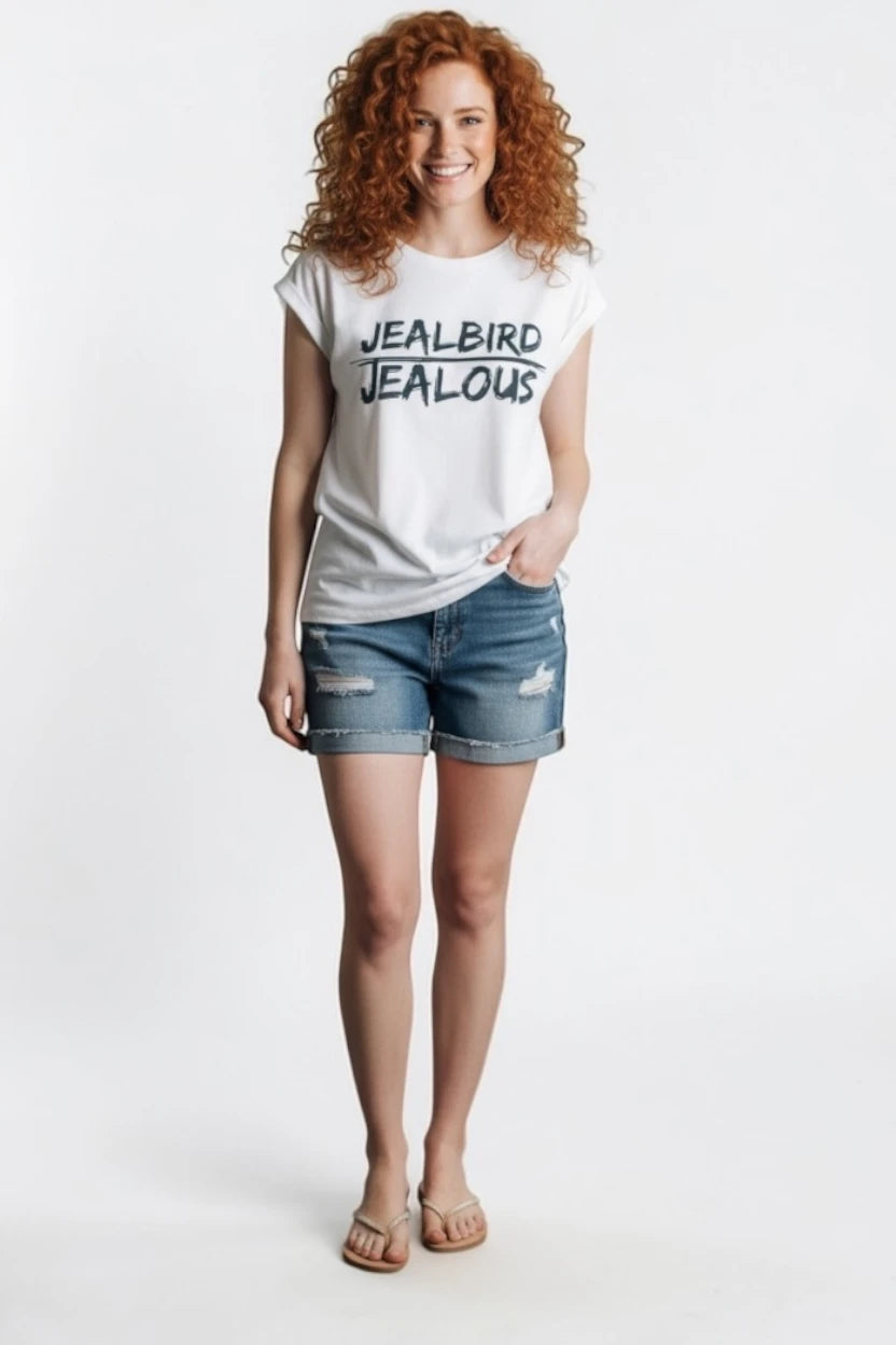 Woman wearing a white muscle t-shirt with JEALBIRD JEALOUS design and denim shorts