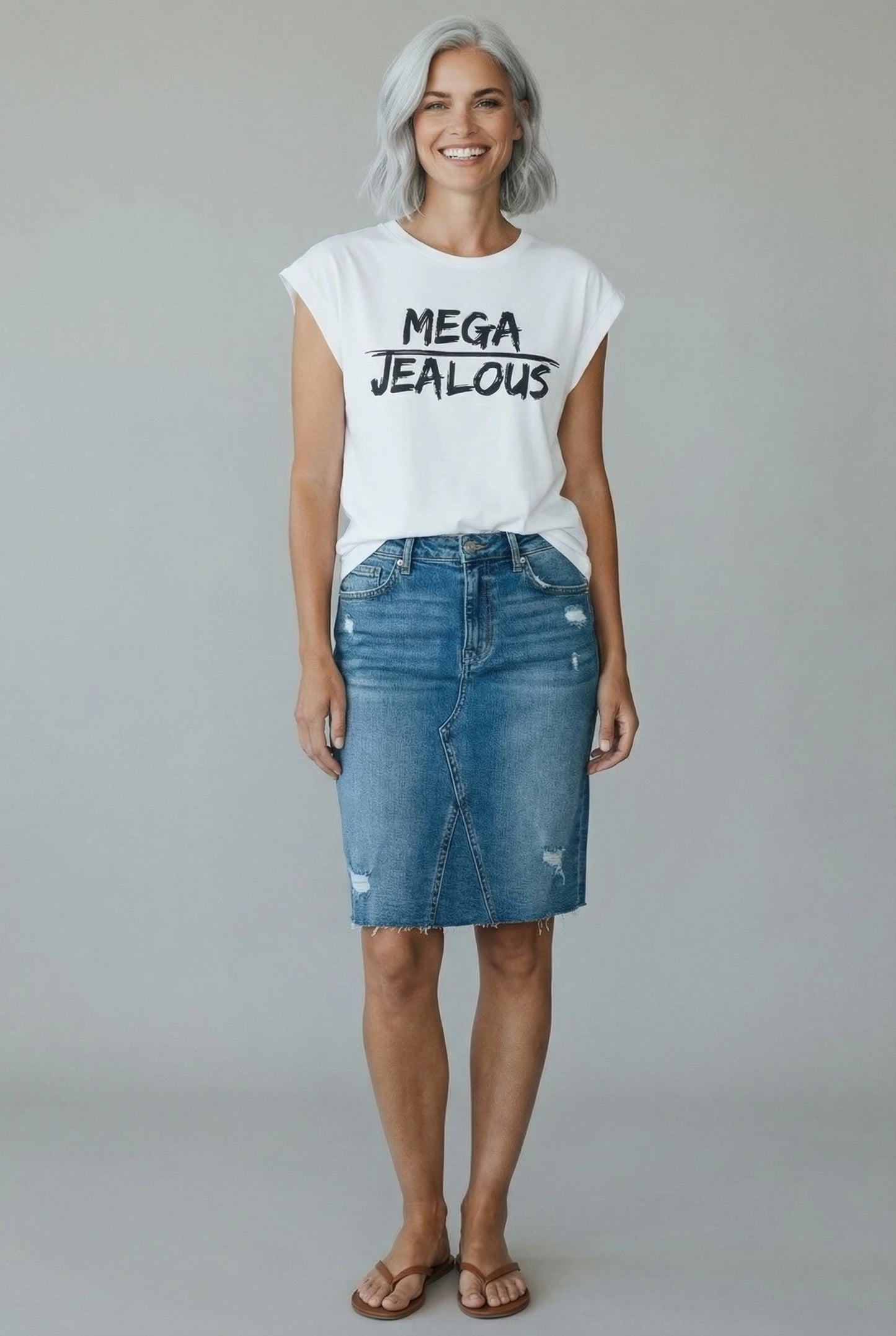 Woman wearing a white muscle t-shirt with MEGA JEALOUS design and a denim skirt