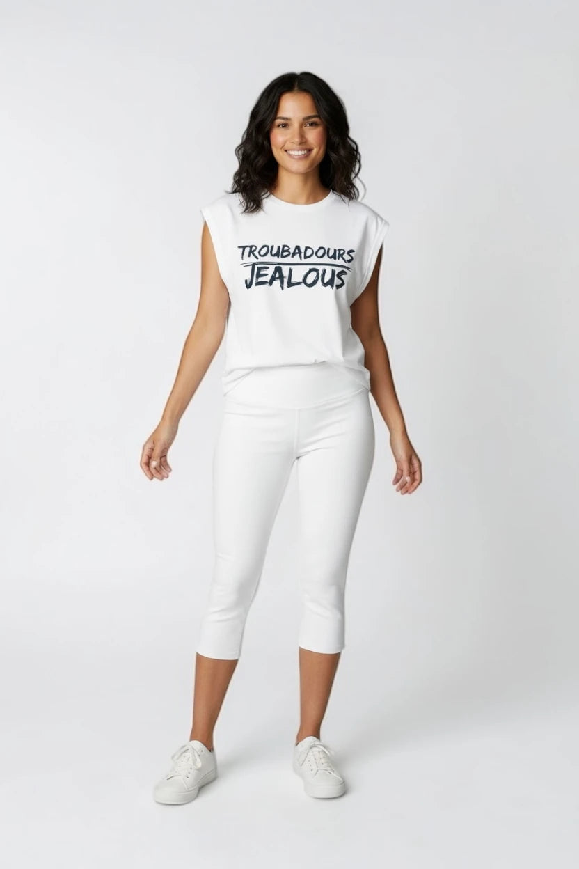Woman wearing a white muscle t-shirt with TROUBADOURS JEALOUS design and white pants