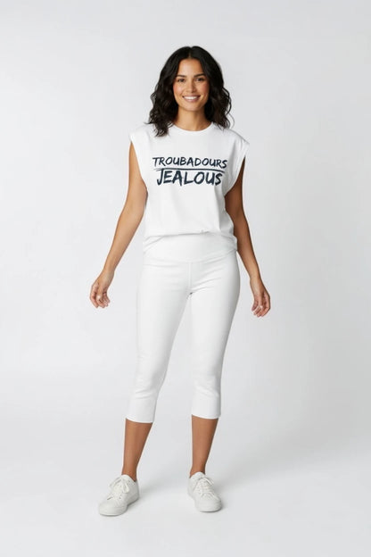 Woman wearing a white muscle t-shirt with TROUBADOURS JEALOUS design and white pants