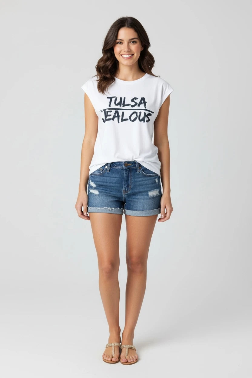 Woman wearing a white TULSA Jealous Tee with denim shorts